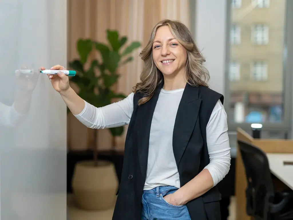 Businessfoto wo Person an einem Whiteboard zeichnet